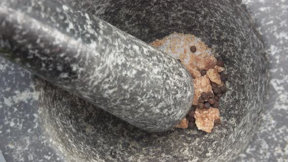Closeup of Brown Sugar and Peppers Falling Into the Grey Stone Mortar
