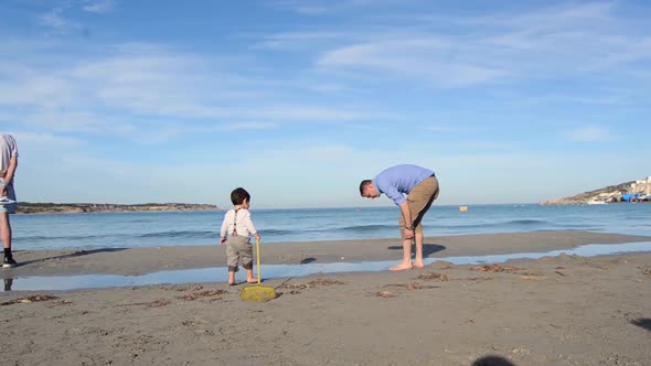 LONG SHOT moving away from camera Father and son playing on the beach of Malta on a clear beautiful