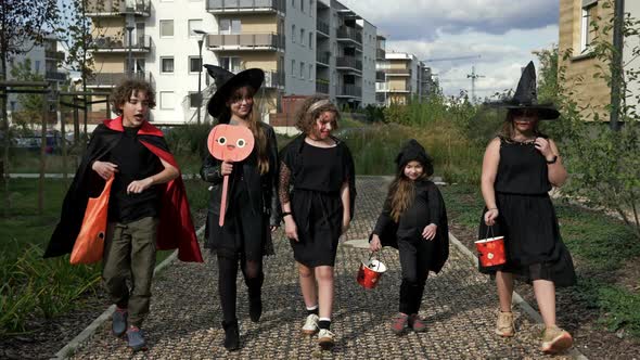 Group of Children in Black Fancy Dress with Frightening Makeup on Their Faces is Running Down the