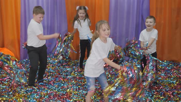 Colored Ribbons Fly in Different Directions. Bright Children's Emotions. Children Jump Holding Foil