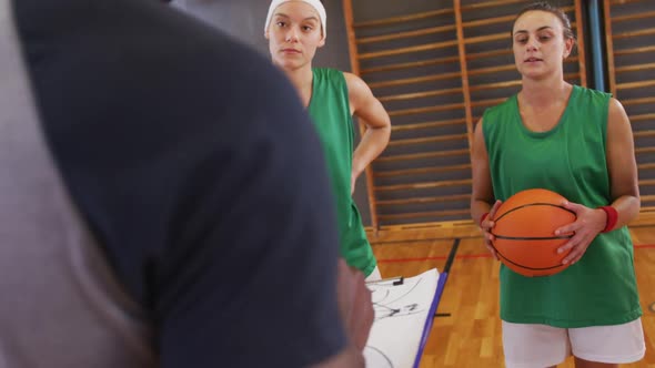 Diverse female basketball team and coach discussing game tactics