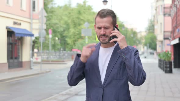 Man Getting Angry on Phone Call While Walking Down the Street