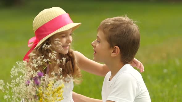 Little Boy Gives a Bouquet of Wild Flowers To a Girl. Slow Motion