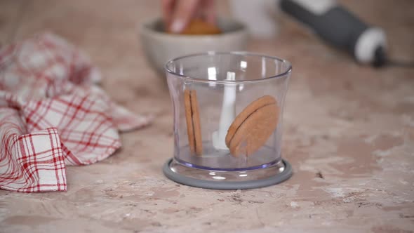 Female Putting Cookies to Food Processor to Make Fine Crumbs for a Cake Base.