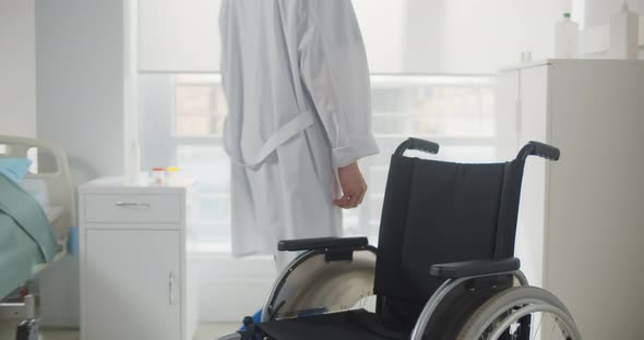 Male Nurse Pushing an Empty Wheelchair in Hospital Ward