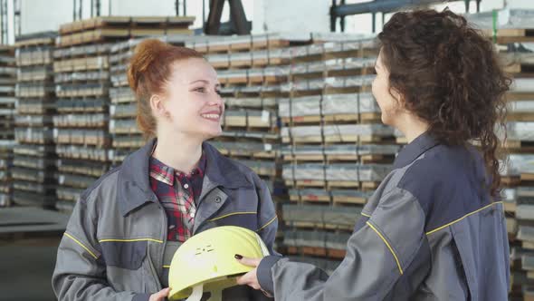 Beautiful Female Factory Worker Receiving a Hardhat From Her Colleague