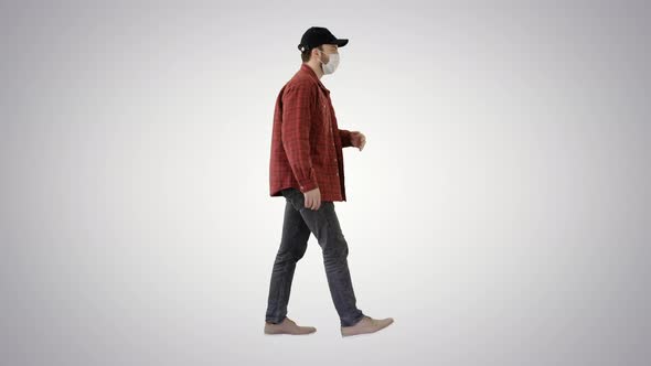 American Farmer in a Cap and Medical Mask Walks Along on Gradient Background.