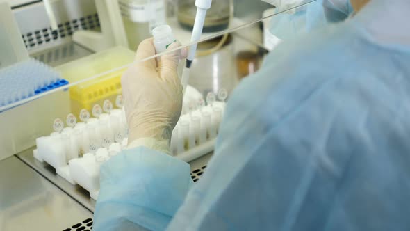 Scientist Working in Sterile Genetics Laboratory with Pipette in Medical Dressing Gown