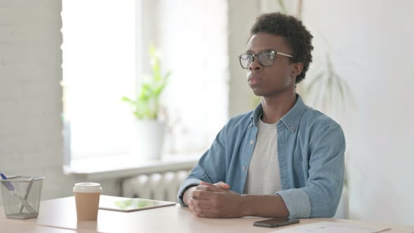 Pensive Young African Man Thinking While Sitting in Office