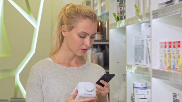 Female Using Smart Phone, Browsing Information Online While Shopping Medication