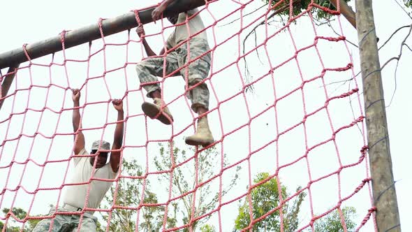 Military soldier climbing rope during obstacle course