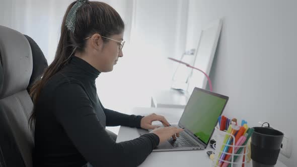 A Young Student of Colombian Universitary Sitting at a Desk and Using Her Laptop