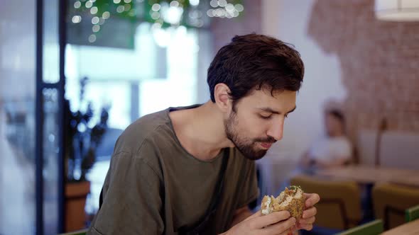 Unshaven c Man Eats Meat Burger with Pleasure Bites Burger with His Mouth