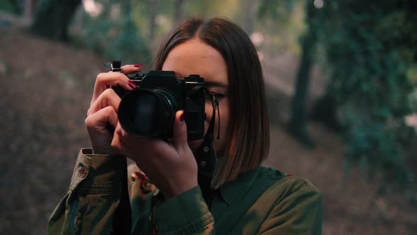 Girl taking pictures with camera in nature. Close-up, handheld