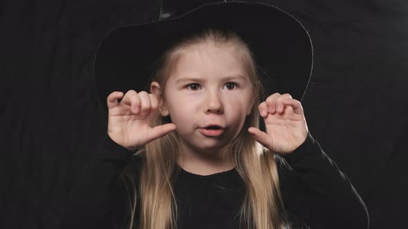 Little Pretty Girl Witch in Black Dress and Hat Screaming at Dark Background