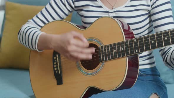 Close Up Of Woman's Hands Playing A Guitar At Home