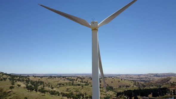 Aerial dolly shot passing a wind turbine close by, overlooking a vista of hills and trees