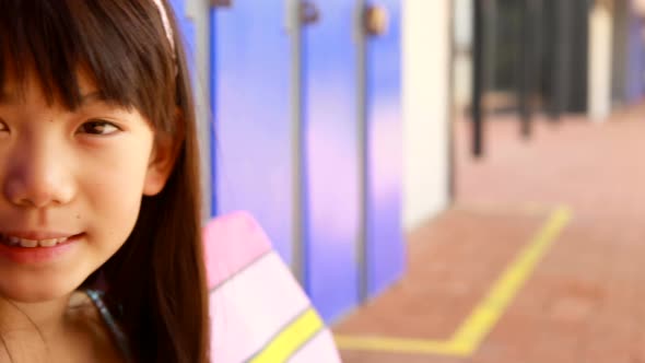 Portrait of happy schoolgirl sitting in locker room 4k