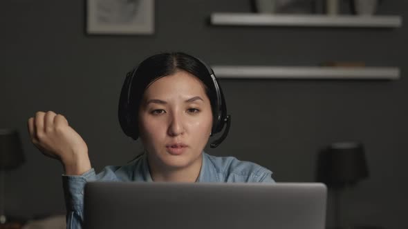 Close up of Young asian woman wears headset conference calling on laptop talks with clients
