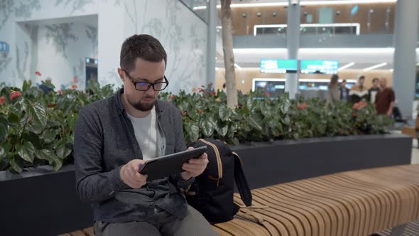 Man is Tapping and Swiping on Tablet in Waiting Room of Airport Istanbul