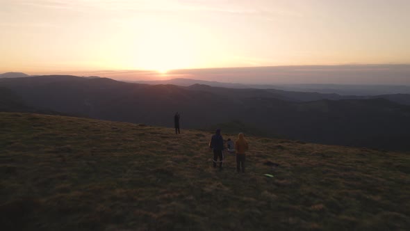 Flying Over Group of Excited Hikers Watching the Sunset at the Top of the Mountain