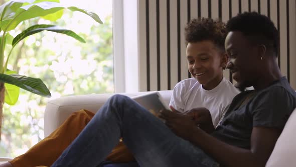 Funny Dad and Teen Son Watch Video on Tablet and Laugh