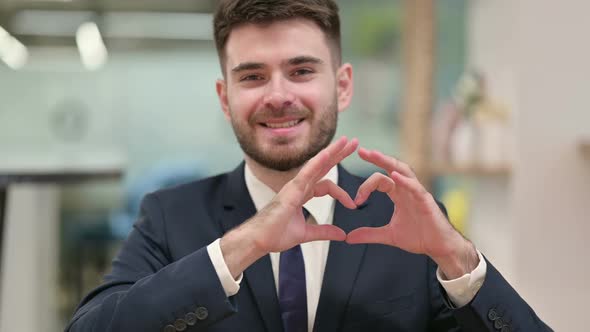 Loving Young Businessman Showing Heart Sign