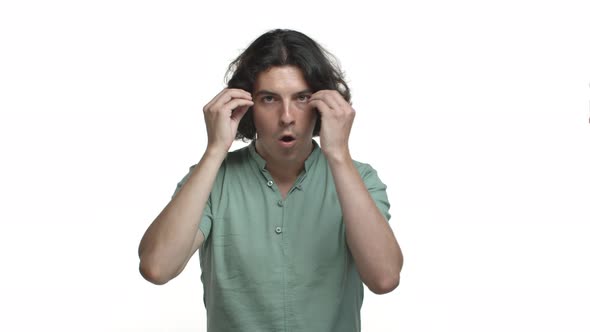 Handsome Hispanic Man with Long Dark Hair Wearing Green Shirt Looking Shocked and Showing Mindblow