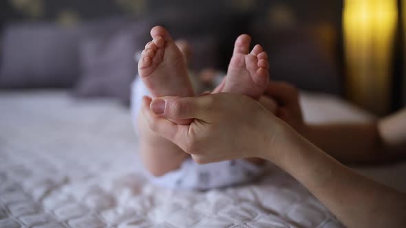 Mom is Caressing Baby's Feet on a Bed