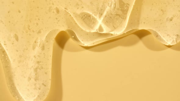 Beige Yellow Transparent Cosmetic Gel Fluid With Molecule Bubbles Flowing On The Plain Surface