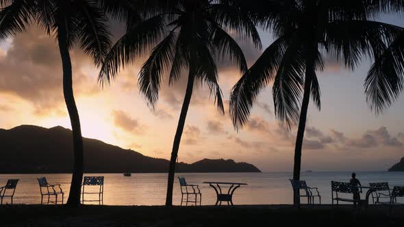 Lonely Man Walking On Tropical Beach At Sunset