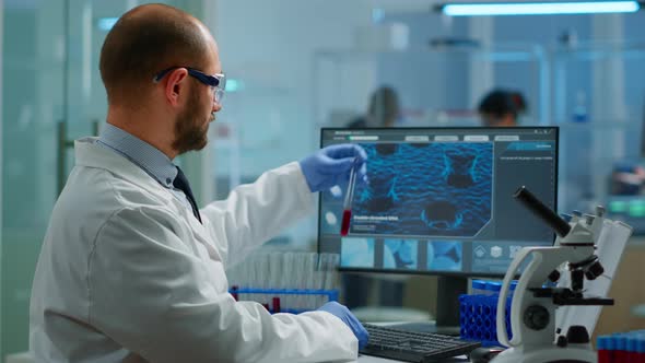 Scientist in Lab Coat Analysing Blood Sample From Test Tube