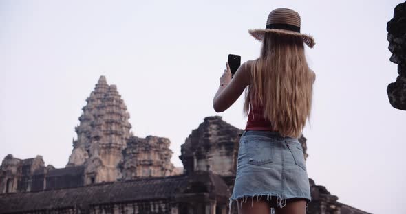 A Young Traveler With Long Blonde Hair Takes a Snap of the Spectacular View With a Camera Phone