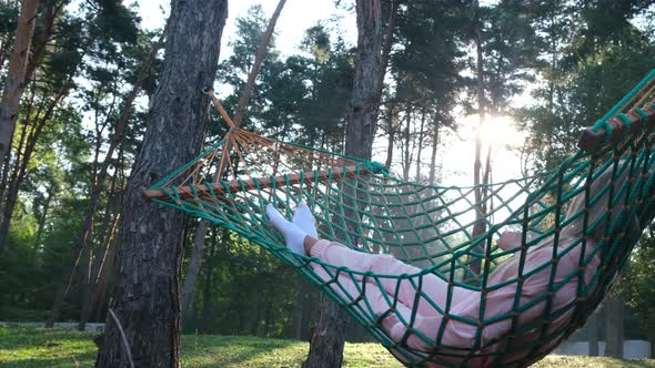 Young beautiful woman enjoying and relaxing in a hammock in the woods.