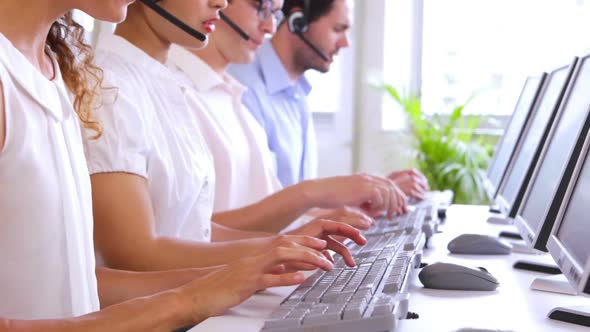 Row of Call Centre Agents Typing at their Desk