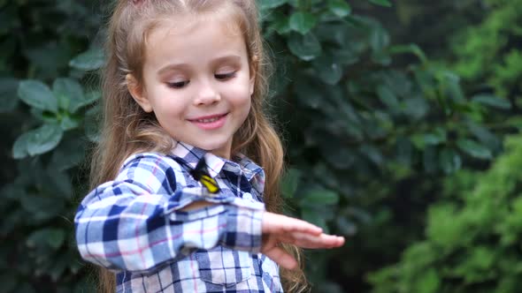 A Girl Holds a Butterfly on Her Hand Smiles