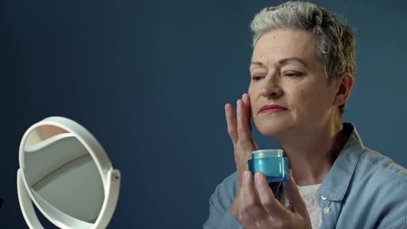 An Elderly Woman Applies an Antiaging Moisturizer