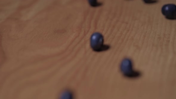 Blueberries Rolling Down a Wooden Board, Closeup. Slow Motion