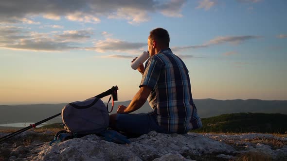 Man Drinks a Hot Drink From Thermos Bottle at Evening on a Mountain Hike Travel Peak Spbd