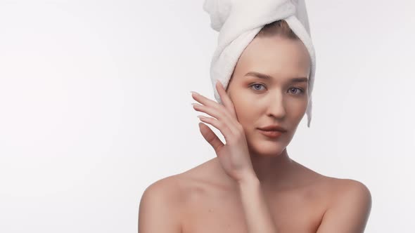 Industry of beauty. Attractive woman with towel on head after spa looks into camera