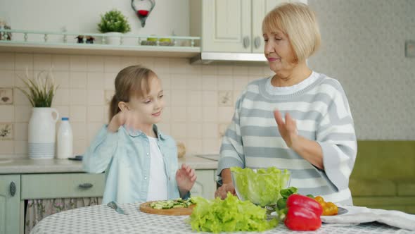 Adorable Blond Child Helping Granny in Kitchen Making Salad Doing High-five