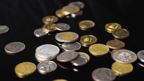 Close-up of coins from different countries of the world falling against a black background
