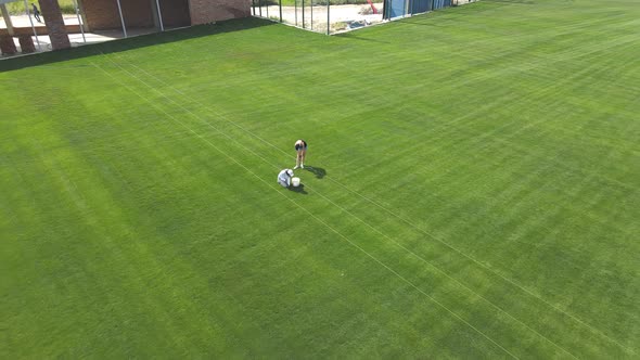 The Girls Weed the Grass on the Football Field By Hand