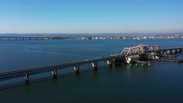 A high angle shot over elevated train tracks crossing a bay in Queens, NY. The camera truck left & p