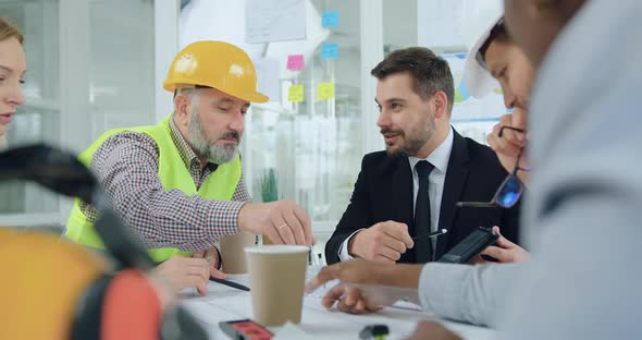 Boss and His Female Colleague Discussing with Professional High-Skilled Mixed Races contractors