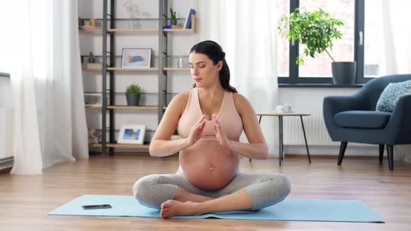 Happy Pregnant Woman with Phone Doing Yoga at Home