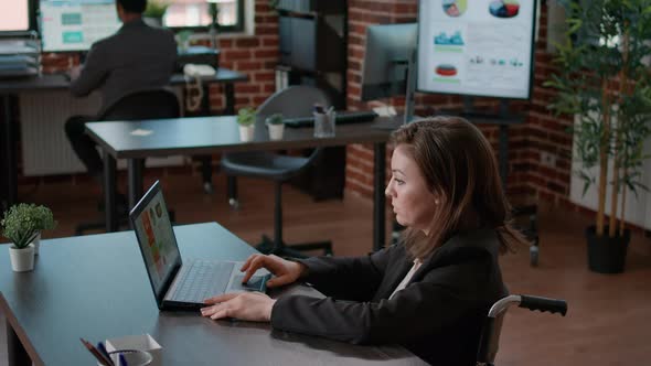 Portrait of Office Worker in Wheelchair Using Laptop at Desk