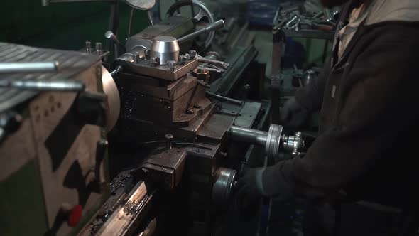 White Man Is Turning a New Part on a Lathe Inside a Large Factory