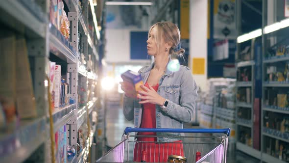 Blond Woman Chooses a Box of Cereals and Puts It Into a Cart