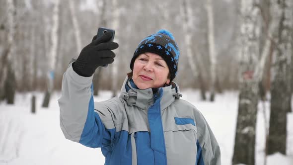 Aged Woman Is Taking Selfie In The Forest In A Winter Day